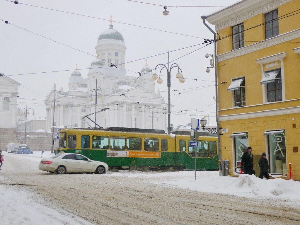Ghostly image of Helsinki Cathedral in white behind a green tram and a yellow building