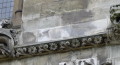 Stone wall with a carved row of flowers and leaves, at each end there is a strange best. One looks like a bat and the other is more like a snarling lion.