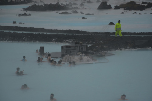 A lifeguard walks the perimeter as bathers gather around the silica mud station.